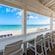 Chairs at a covered patio bar facing a beach with lounge chairs